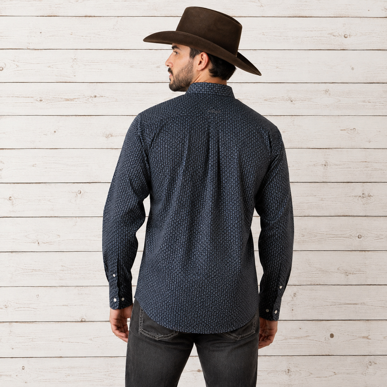 A man wearing a dark navy blue patterned long-sleeve button-down shirt and a brown cowboy hat