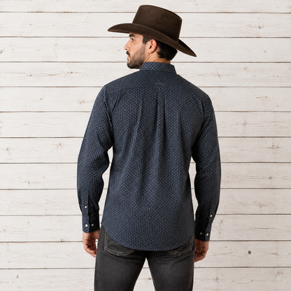 A man wearing a dark navy blue patterned long-sleeve button-down shirt and a brown cowboy hat