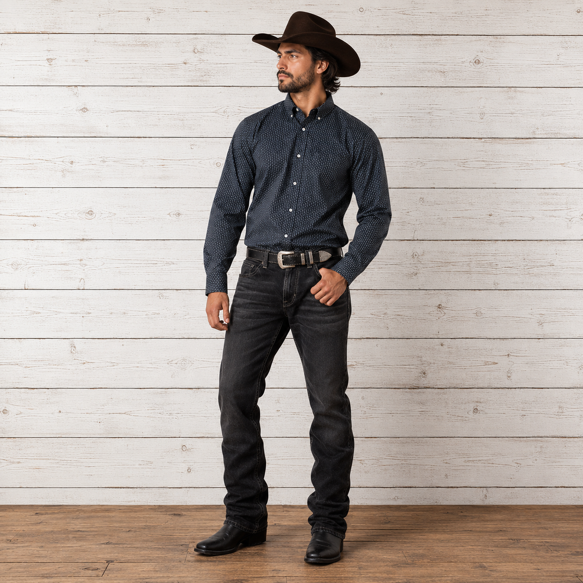 A man wearing a dark navy blue micro-patterned long-sleeve button-down shirt, dark gray jeans, a brown cowboy hat, and black boots