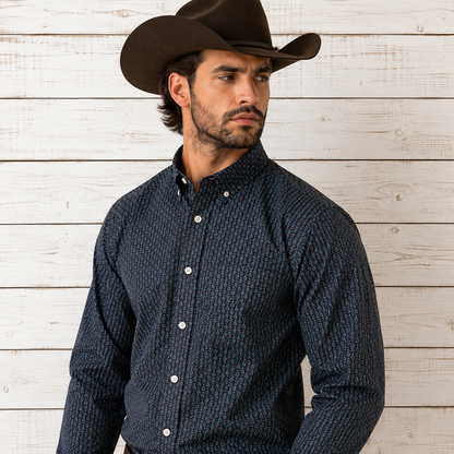 A man wearing a dark navy long-sleeve button-down shirt with a small geometric pattern, paired with a brown cowboy hat
