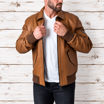 A man wearing a brown leather bomber jacket over a white t-shirt and dark jeans