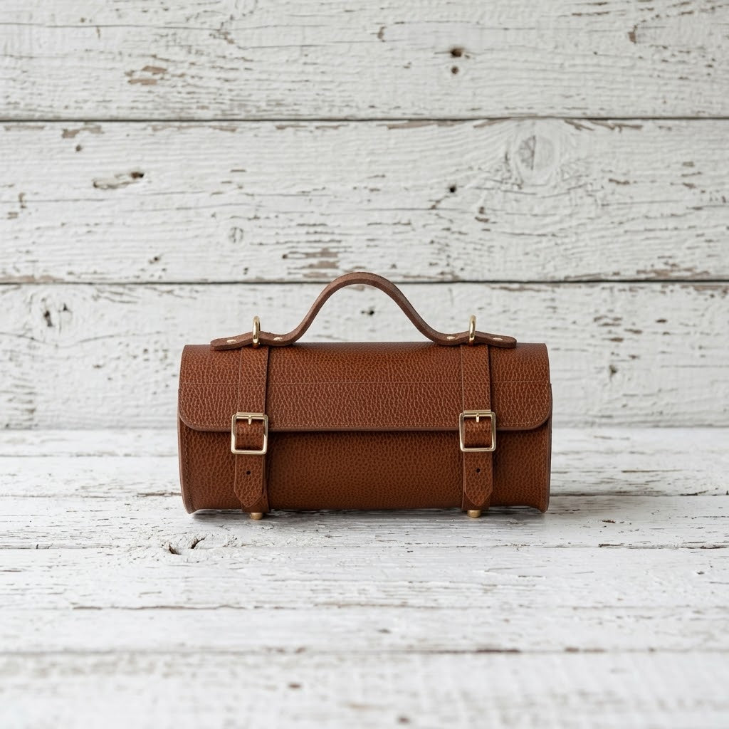 Handcrafted cognac brown bison leather barrel bag with brass buckles and top handle 