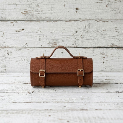 Handcrafted cognac brown bison leather barrel bag with brass buckles and top handle 