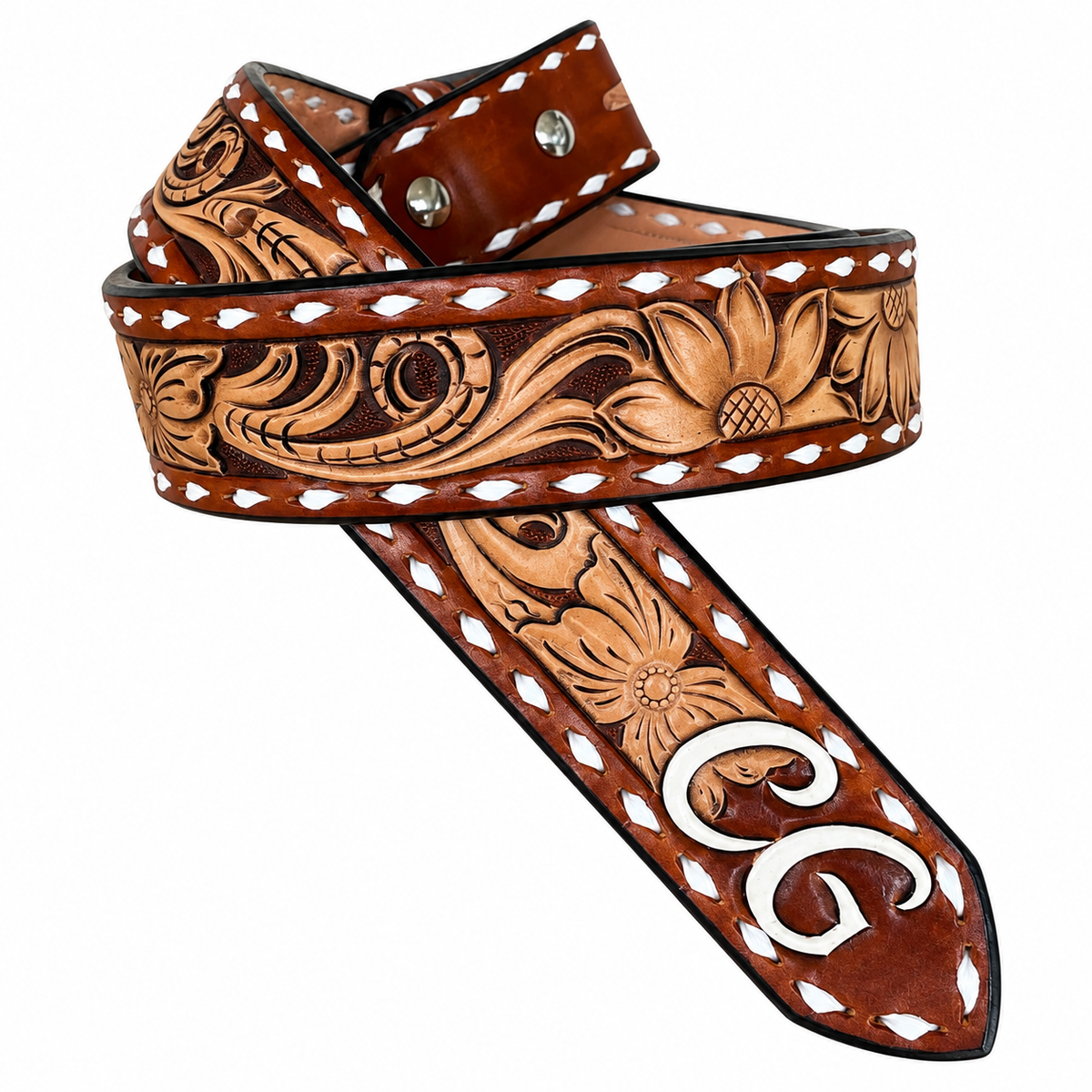A brown tooled leather belt with floral and scroll designs, featuring white stitching, silver metal rivets, and a large white monogram 'G' on the tip, shown on a white background.
