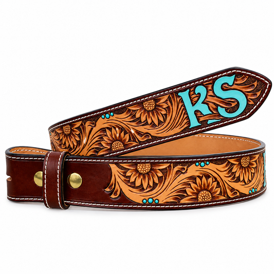A tooled leather belt with floral sunflower designs and turquoise monogram initials 'KS' on the keeper, displayed on a clean white background.
