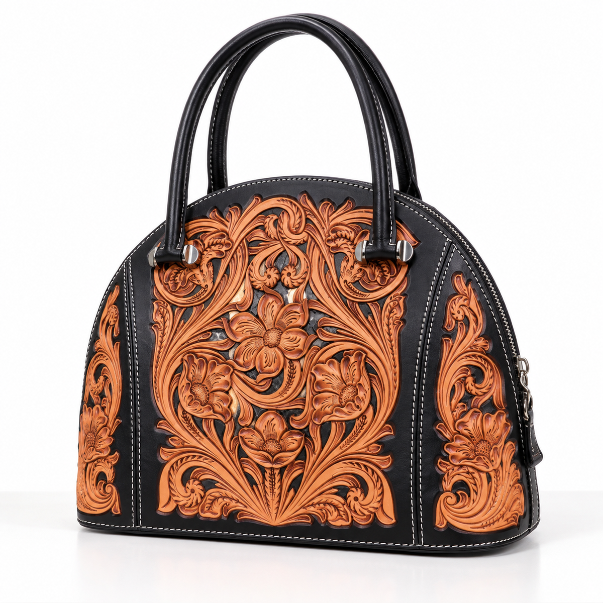 A black leather dome handbag with intricate, hand-tooled floral and scroll patterns in a warm brown/cognac tone, featuring dual top handles and silver-tone hardware.