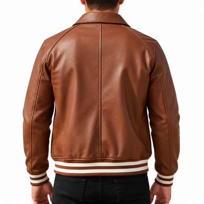 A man viewed from the back wearing a brown leather varsity-style jacket with cream and dark brown striped ribbed cuffs and hem, paired with black jeans against a plain white background.