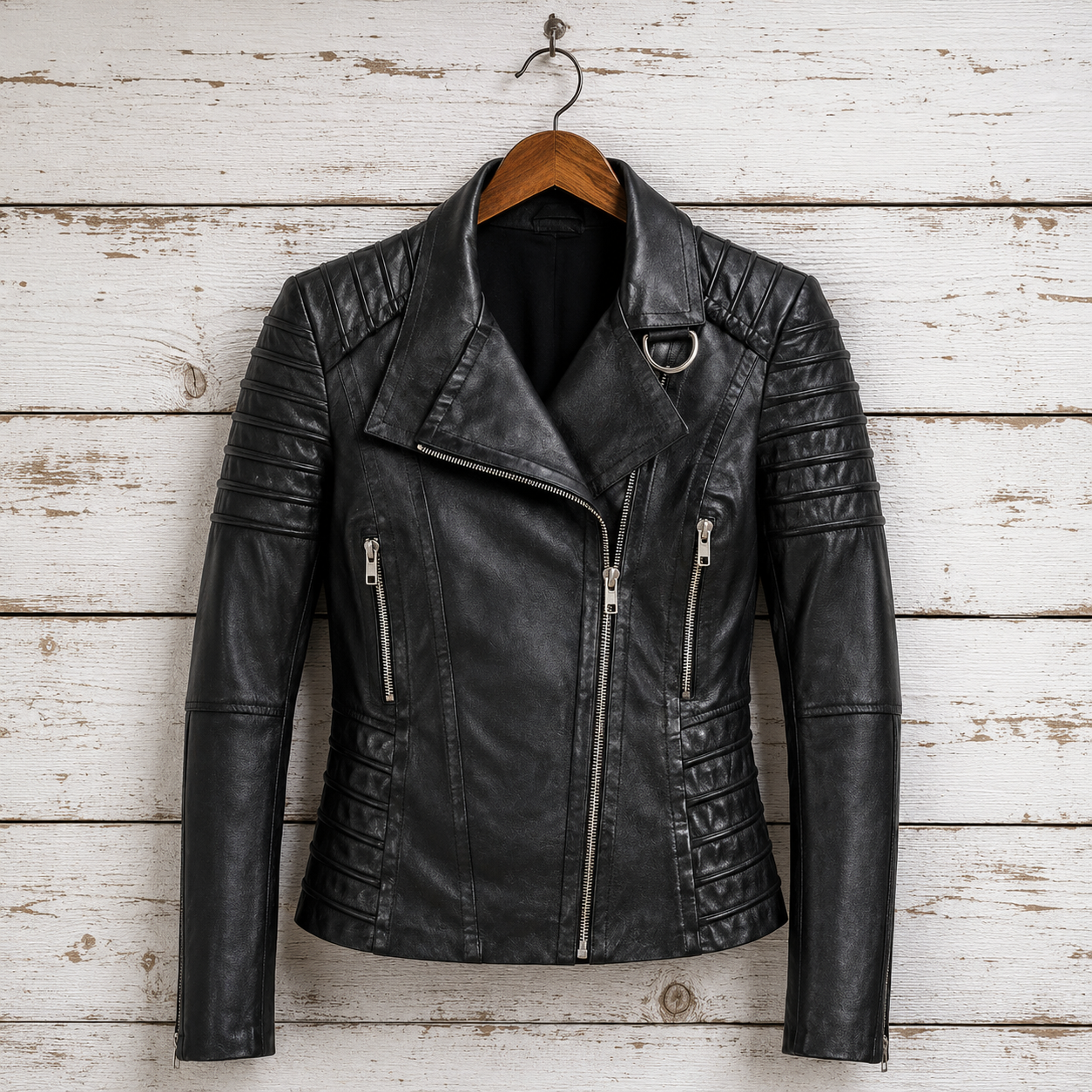 Black leather moto jacket with quilted details, hanging on a wooden hanger 
