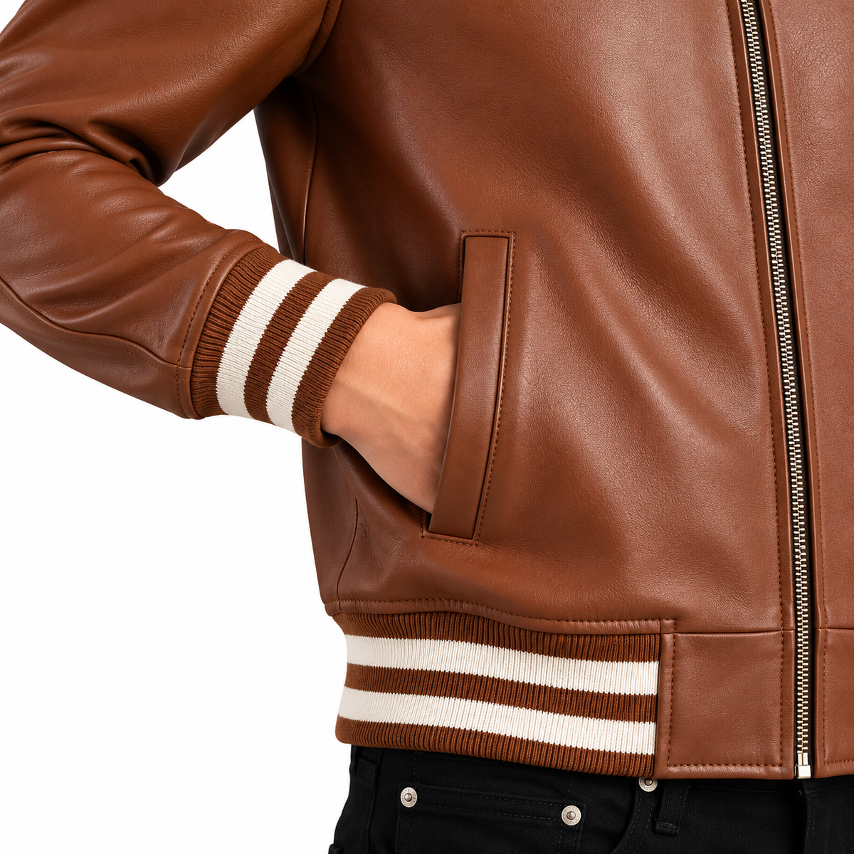 Close-up of a brown leather jacket with cream and brown striped ribbed cuffs and hem, shown on a model with a hand in the pocket against a white background.