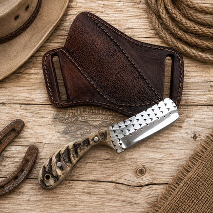 A handcrafted knife with a rasp steel silver blade and a carved tan handle, displayed diagonally next to its dark brown leather sheath on a rustic wooden surface with western-themed props.