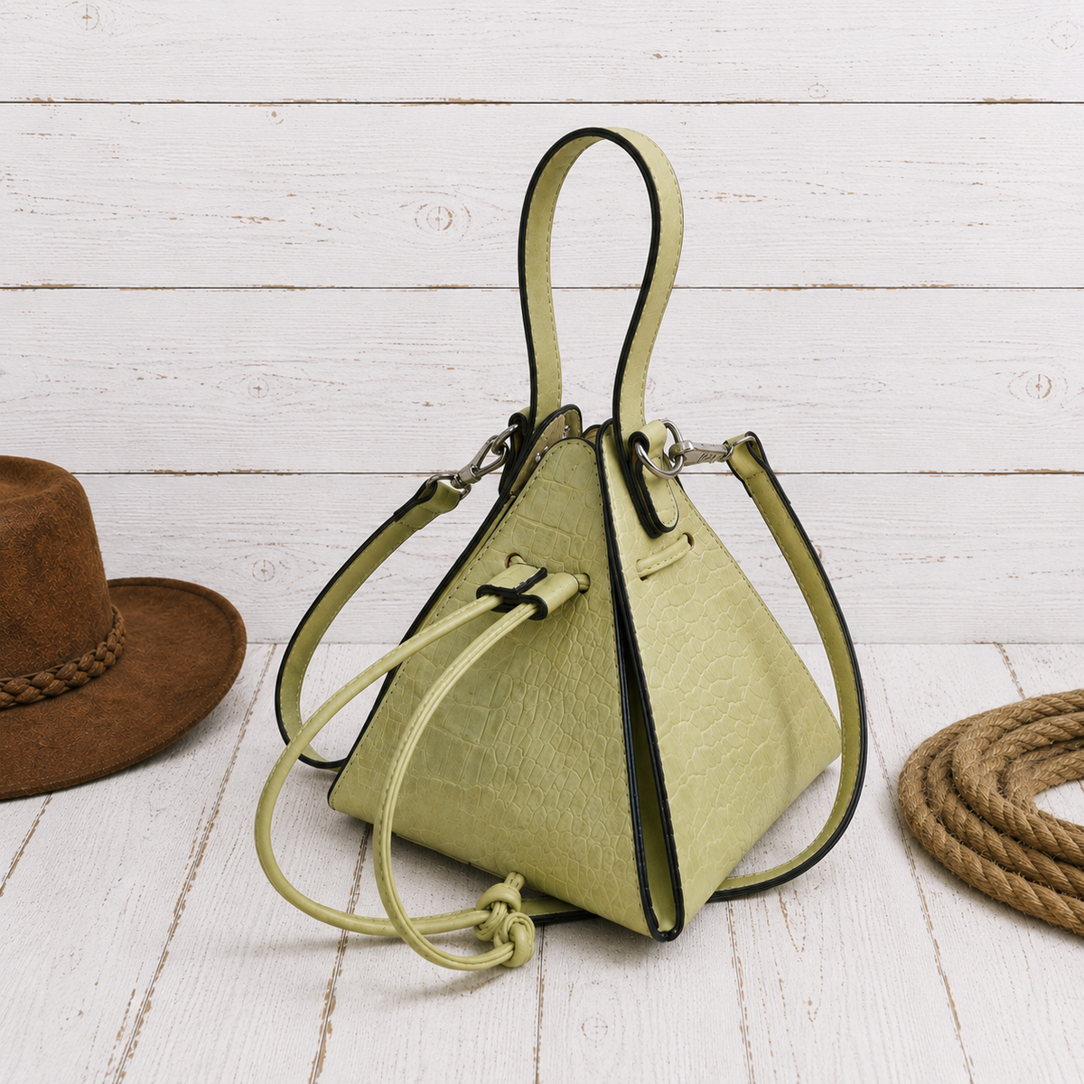 A light olive green textured leather bucket bag with black trim