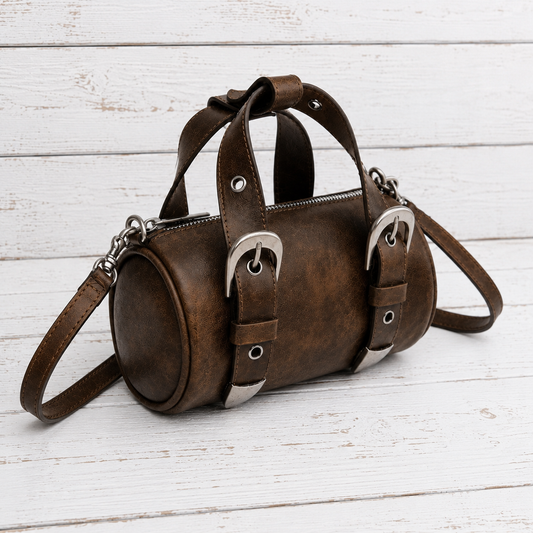 A brown distressed leather duffel bag with silver buckle details and top handles